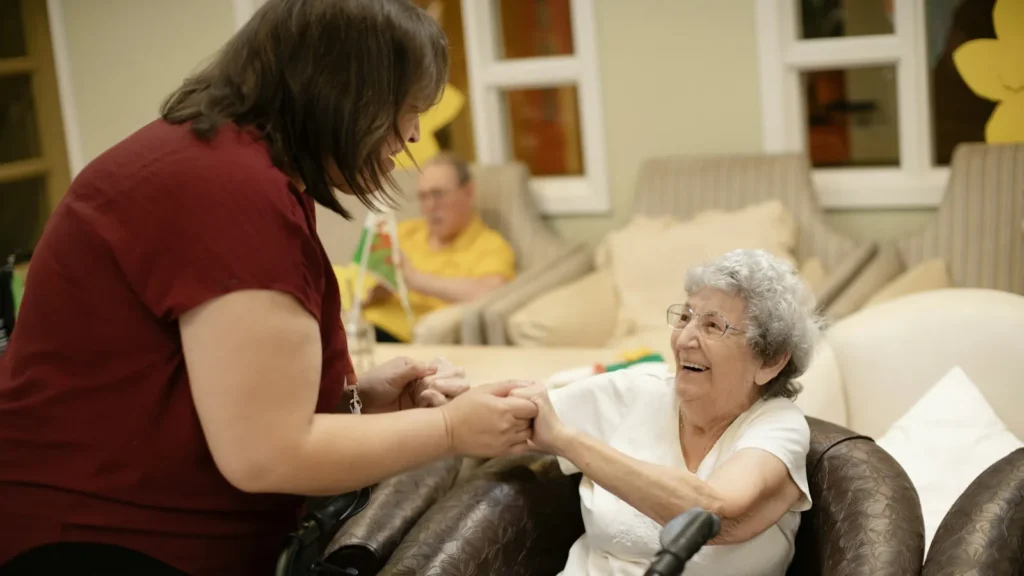 Caregiver holding hands with a smiling older woman in her home